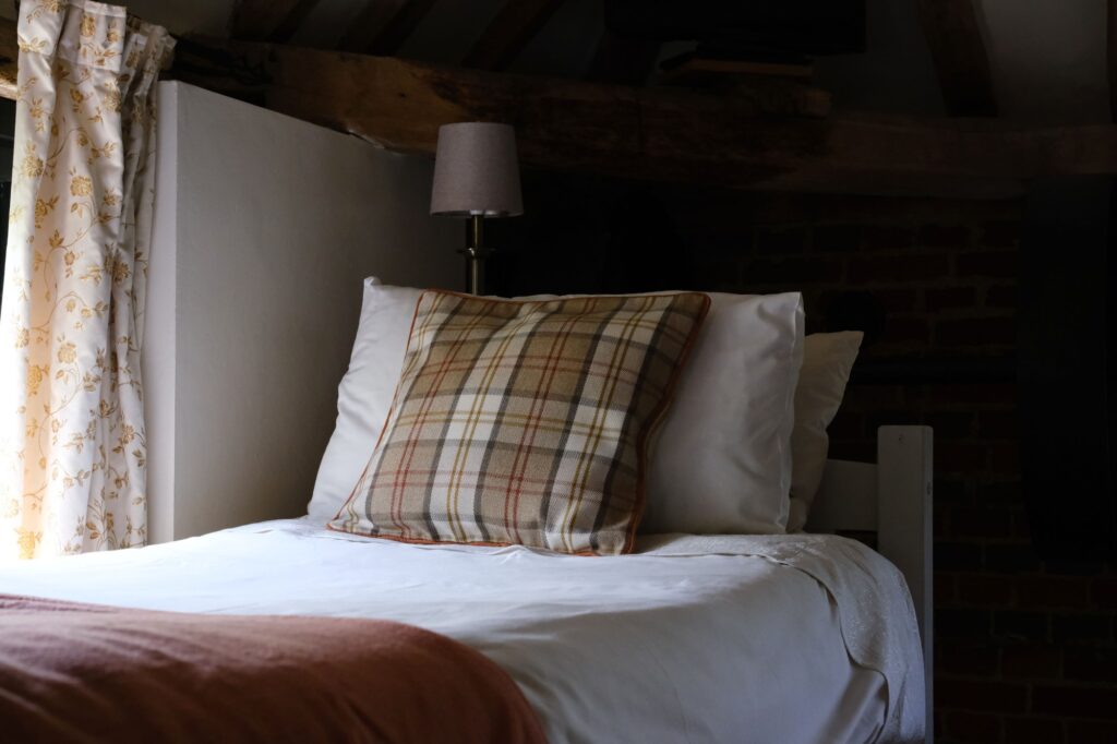 A single bed with a checked cushion under the old beams