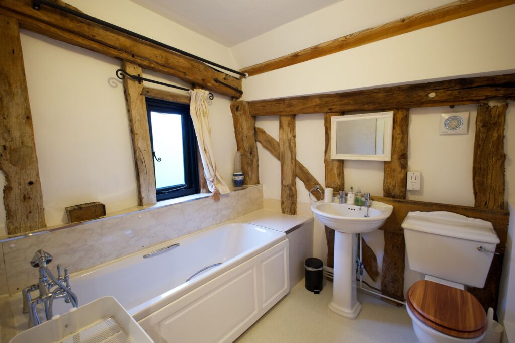The family bathroom with a bath, basin and exposed timber frame