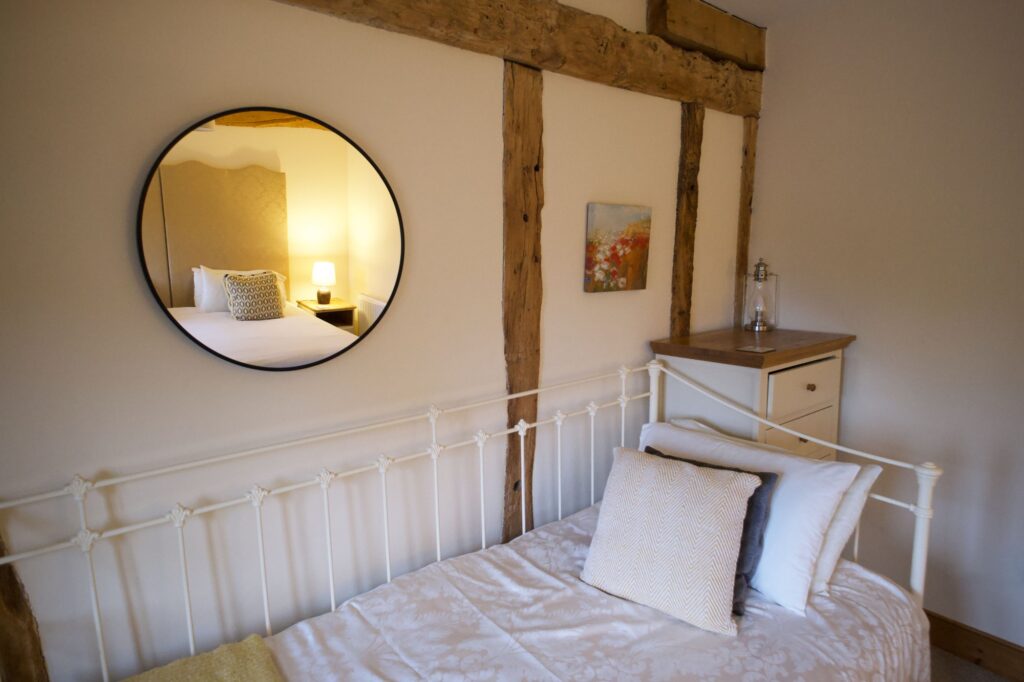A white iron day bed under a round mirror and oak beams