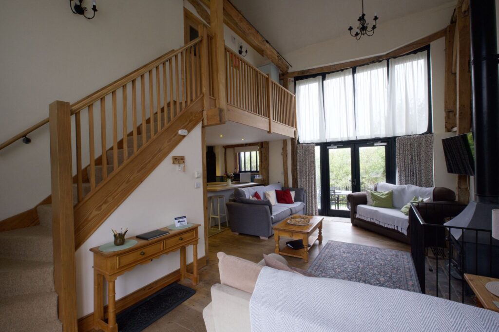 The open-plan sitting room with the staircase, wood burner and French doors