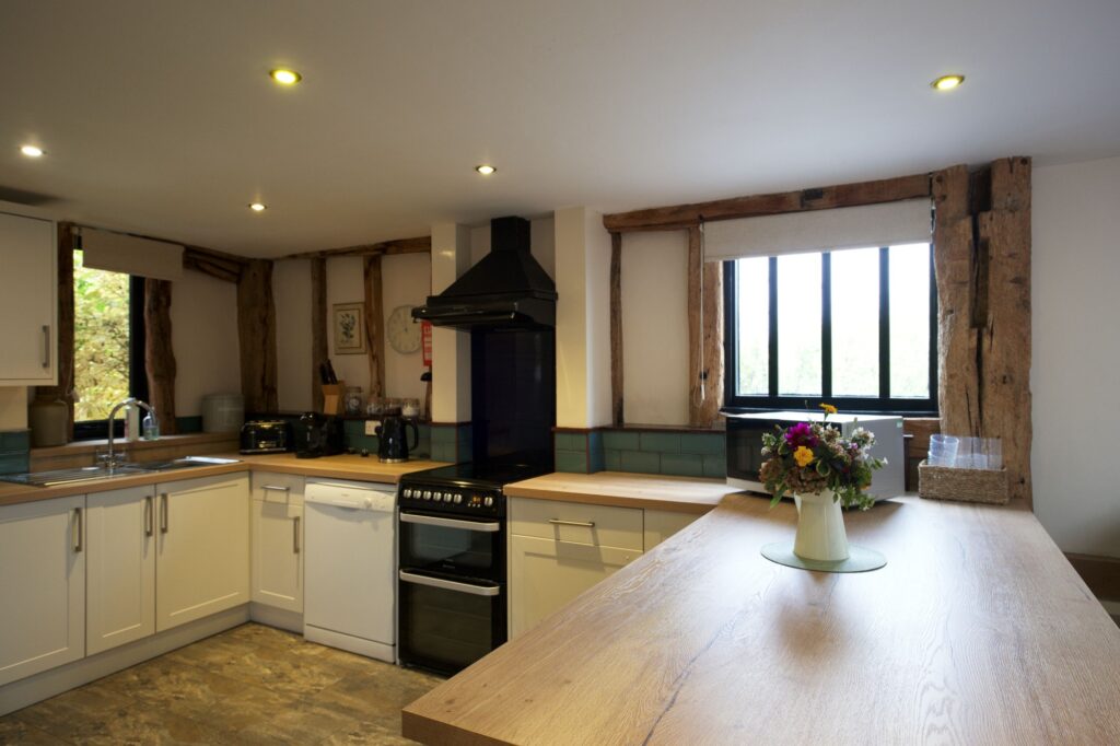 The kitchen with oak worktops and a vase of garden flowers