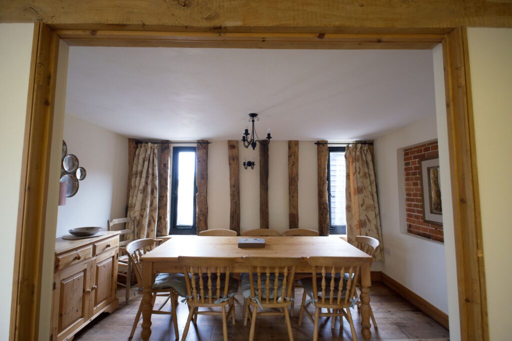 The dining room with a pine table for eight between oak posts