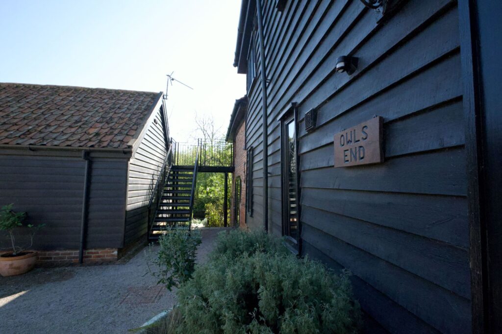 The Owls End name sign on the weatherboarding beside the courtyard