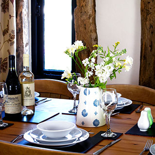 The dining table laid for dinner with wine and a jug of flowers