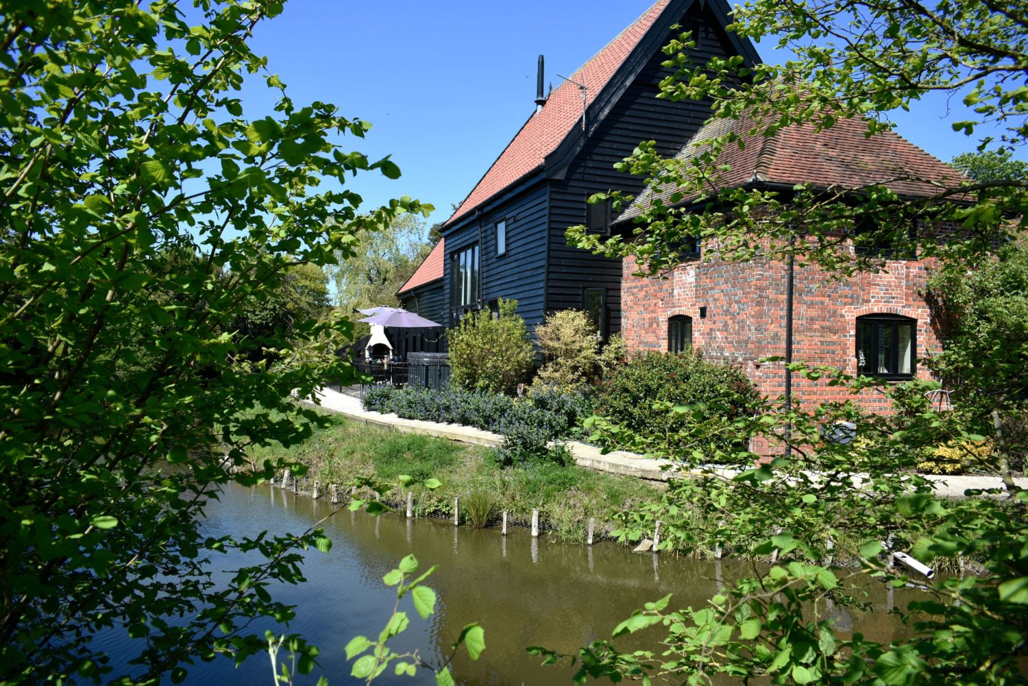 Owls End and its brick milling section seen across the moat on a sunny day