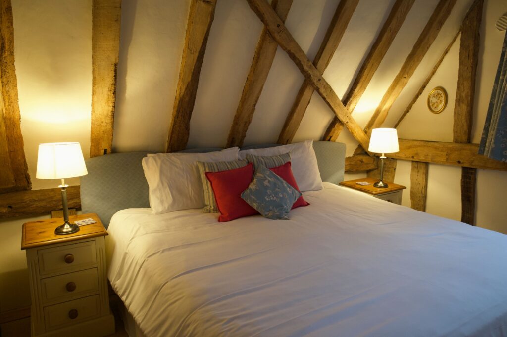 The super king bedroom upstairs, lit by bedside lamps under criss-cross beams