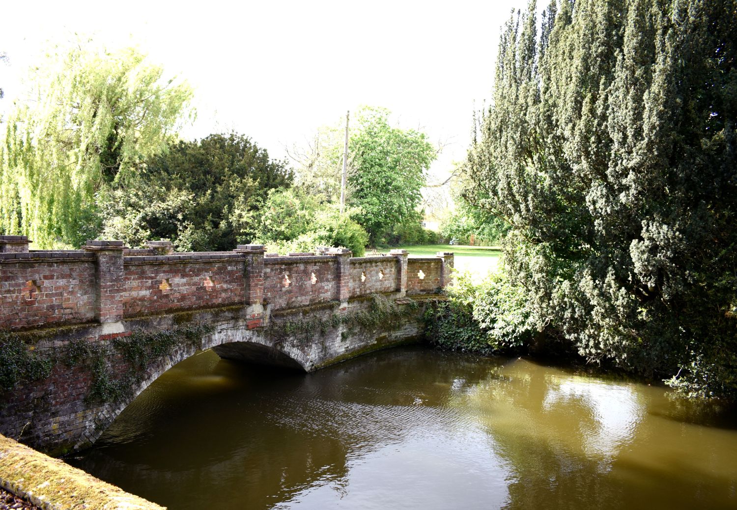 The old brick bridge over the moat, with willow and yew trees beside it