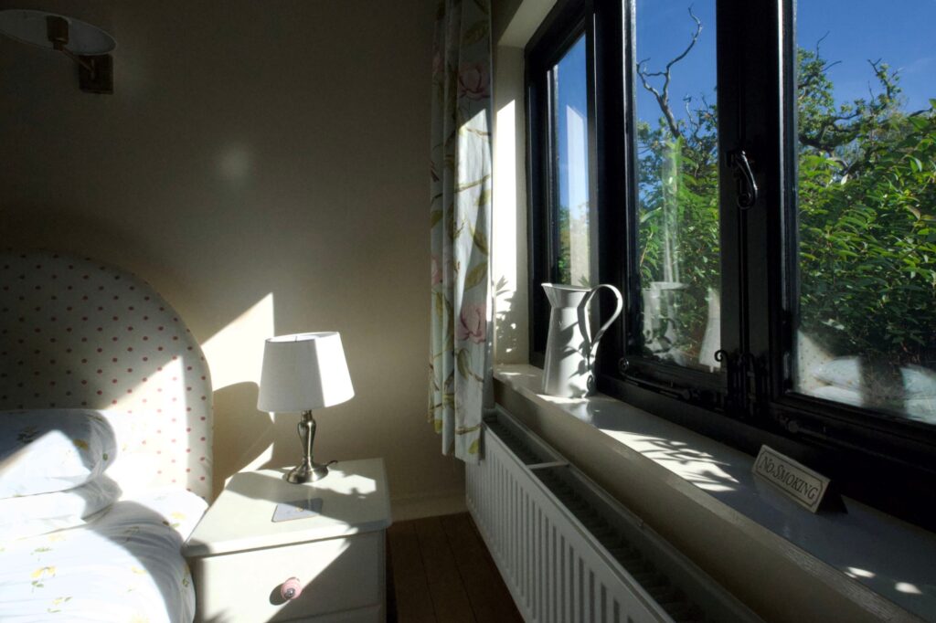 Morning sun through the bedroom window, with a white jug on the sill