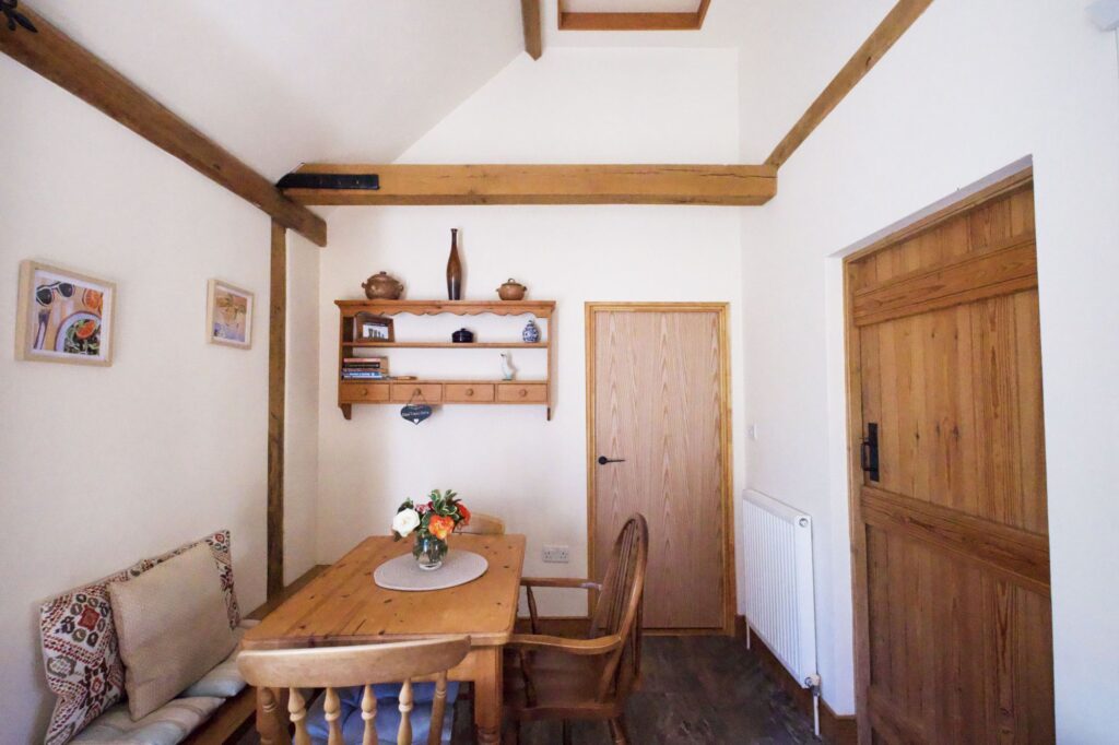 The dining corner with a pine table, bench seat and garden flowers