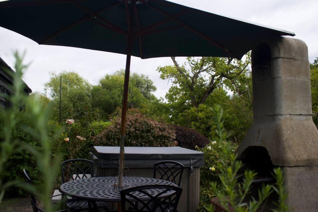The Willow patio with its hot tub, table, parasol and barbecue