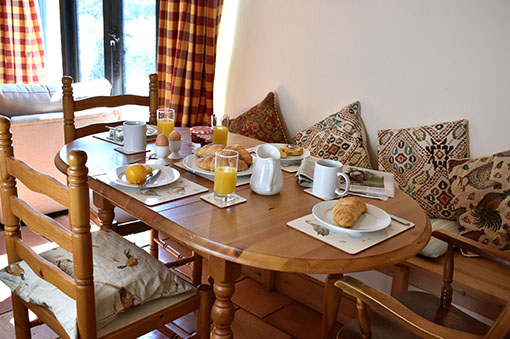 Breakfast laid on the dining table, with croissants, eggs and orange juice