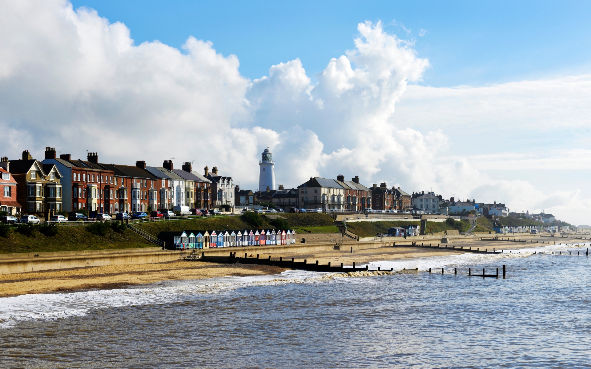 Southwold seafront with its lighthouse, terraced houses and colourful beach huts above the sand