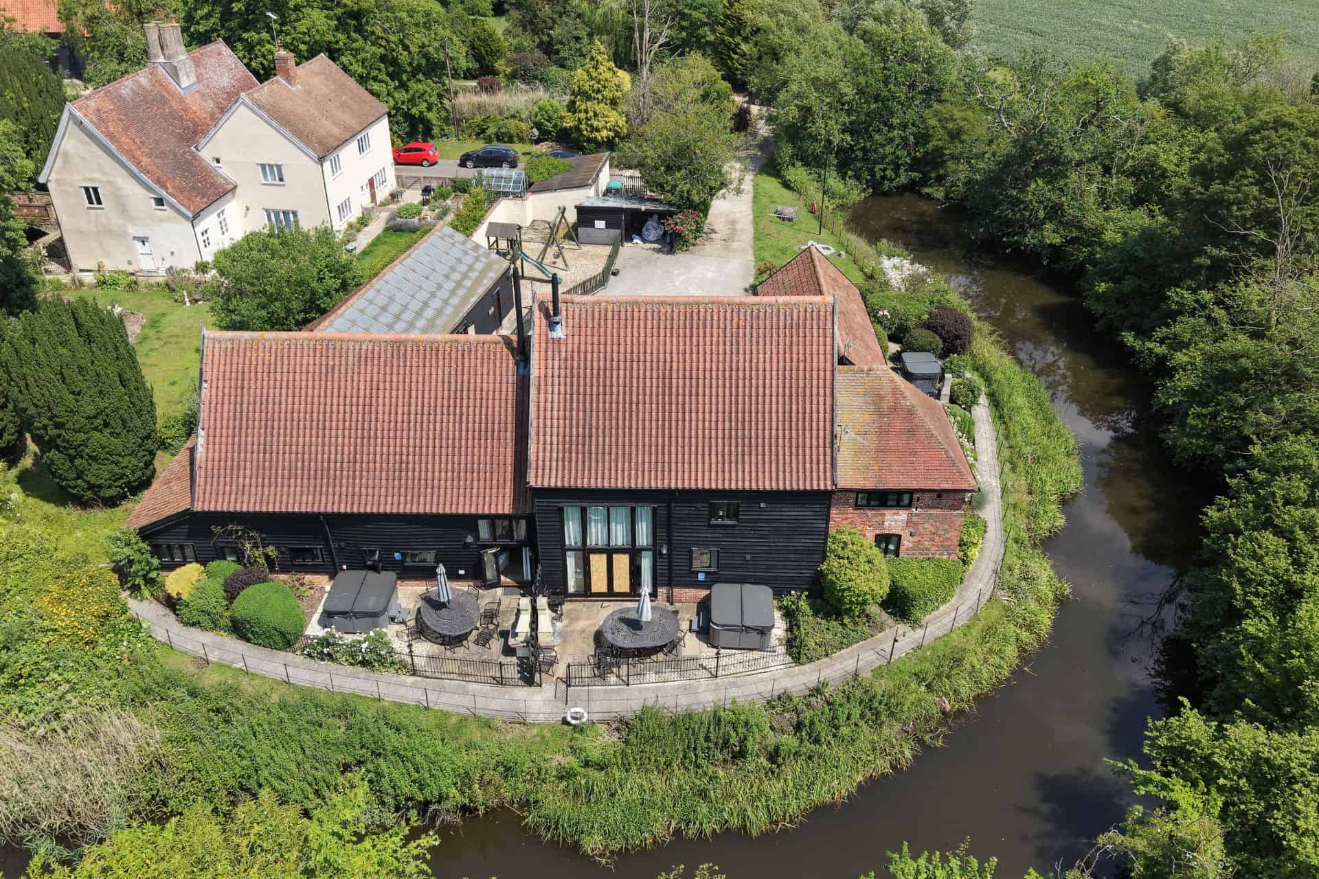 Aerial view of the three cottages, their patios and hot tubs, wrapped by the moat